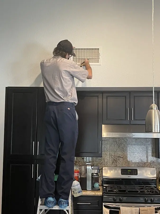 Technician inspecting an air vent during HVAC service in Chesapeake Beach